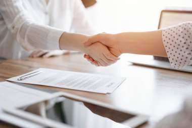 İş adamları kontrat kağıtlarının üzerinde el sıkışıyor. Tahta masaya yeni imzalanmış. Kapatın. Toplantıdaki avukatlar. Takım çalışması, ortaklık, başarı kavramı.