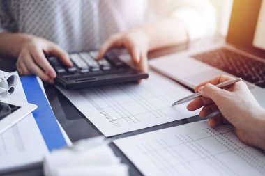 Müşteri için vergi sayarken hesap makinesi ve dizüstü bilgisayar kullanan kadın muhasebeci. İş denetimi kavramları.