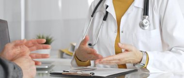 Doktor tıbbi bir randevu sırasında panoya notlar yazıyor, modern bir hastane ofisinde bir hastayla sağlık hakkında konuşuyor. Tıp, sağlık ve bilim konsepti