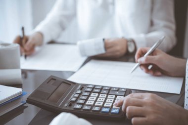 İki muhasebeci vergi veya gelir dengesi saymak için bir hesap makinesi ve dizüstü bilgisayar kullanıyor. İş, denetim ve vergi kavramları.