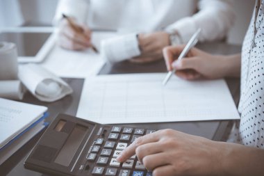 İki muhasebeci vergi veya gelir dengesi saymak için bir hesap makinesi ve dizüstü bilgisayar kullanıyor. İş, denetim ve vergi kavramları.