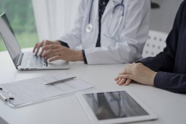 Doktor ve bir hasta klinikte. Kadın hekim laptopta tıbbi geçmiş kayıtlarını dolduruyor. Kapatın. Tıp ve Bilim.