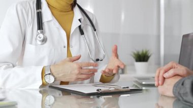 Doktor tıbbi bir randevu sırasında panoya notlar yazıyor, modern bir hastane ofisinde bir hastayla sağlık hakkında konuşuyor. Tıp, sağlık ve bilim konsepti