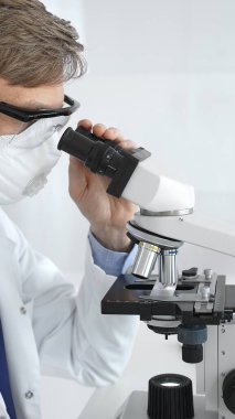 Yeni ilaçlar ve tedaviler geliştirmek için parlak ışıklı bir laboratuvarda mikroskopla gözlem yapan bir bilim adamına yakından bakın. Tıp ve bilim konsepti.