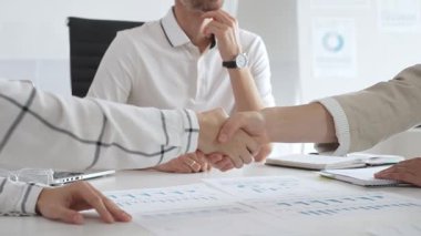 İş adamları iş yeri belgelerinin üzerinden el sıkışıyor, işbirliği ruhunu sembolize ediyor ve işyerindeki başarıyı paylaşıyorlar. El sıkışma kavramı.