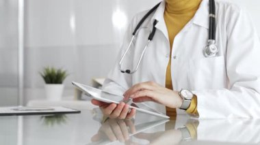 Klinikte dijital tablet kullanan laboratuvar önlüğü ve steteskop giyen bir doktor. Modern tıp ve tele sağlık konsepti. Tıp, sağlık ve bilim konsepti