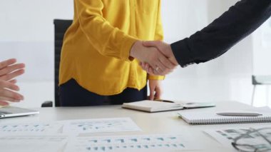 Profesyonel iş arkadaşları anlaşmayı mühürlüyor, ortaklığı alkışlarla, mali evraklarla ve başarılı iş görüşmelerini çevreleyen dijital cihazlarla kutluyorlar.