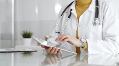 Klinikte dijital tablet kullanan laboratuvar önlüğü ve steteskop giyen bir doktor. Modern tıp ve tele sağlık konsepti. Tıp, sağlık ve bilim konsepti