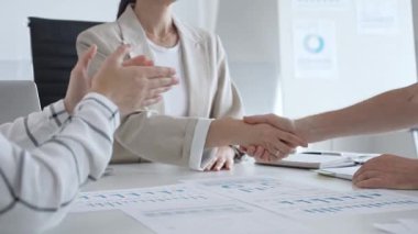 Bej ceketli bir iş kadını başarılı bir toplantının ardından bir işadamıyla tokalaşıyor, şık ve modern ofis ortamında bir iş anlaşmasını sağlamlaştırıyor. El sıkışma kavramı.