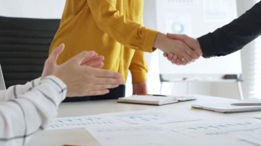 Profesyonel iş arkadaşları anlaşmayı mühürlüyor, ortaklığı alkışlarla, mali evraklarla ve başarılı iş görüşmelerini çevreleyen dijital cihazlarla kutluyorlar.