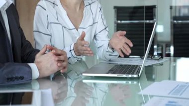 İş ekibi cam masanın etrafında dizüstü bilgisayar ve evrak işleri için toplandı. Elleri analitiğe ve ofis toplantısındaki raporlara işaret ediyor. İş insanları kavramı