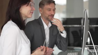 İş arkadaşları bilgisayar, kadın ve erkek birlikte çalışıyor, fikirleri paylaşıyor ve başarılı bir mesleki tartışma ve takım çalışması sırasında gülümsüyor.