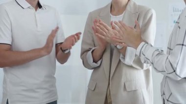 İş arkadaşları ofis toplantı odasında başarılı bir sunum yaptıktan sonra el çırpıyor, başarıyı ve takım çalışmasını kutluyorlar. İş adamları konsepti