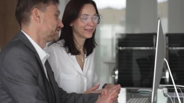 Ofis toplantısında işbirliği yapan iş adamları, bir meslektaşıyla mali raporlar, strateji ve pazar analizi tartışırken masaüstü ekranındaki verilere işaret eden kadın