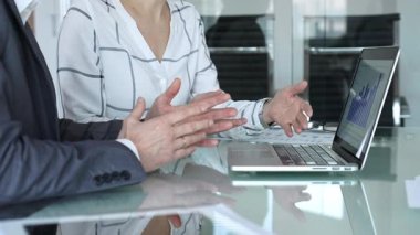 İş ekibi cam masanın etrafında dizüstü bilgisayar ve evrak işleri için toplandı. Elleri analitiğe ve ofis toplantısındaki raporlara işaret ediyor. İş insanları kavramı