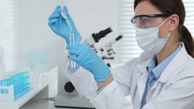 Laboratuvar analizi sırasında cam şişeye kimyasal solüsyon yerleştiren koruyucu giysi araştırmacısı, beyaz arka plan. Tıp, sağlık ve bilim konsepti