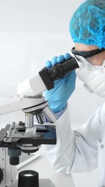 Erkek kıdemli bilim araştırmacısı örnek incelerken hassas mikroskobu kalibre ederek steril laboratuvar ortamındaki çığır açan tıbbi araştırmaları araştırıyor. Tıp ve bilim konsepti.