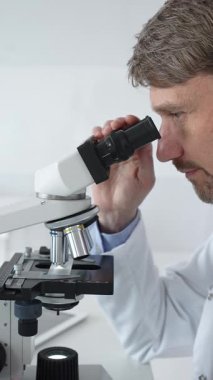 Parlak bir laboratuvarda mikroskopla gözlem yapan bir bilim adamı yeni ilaçlar ve tedaviler geliştirmek için araştırma yapıyor. Tıp ve bilim konsepti.