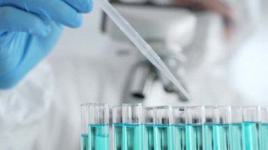 Mavi koruyucu eldivenler giyen bilimsel araştırmacıların ellerini kapatın. Tıbbi araştırma yaparken sıvıyı test tüplerine dikkatlice yerleştirin. Tıp ve bilim konsepti.