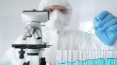 Koruyucu ekipman giyen bilimsel araştırmacıları kapatın, tıbbi araştırma yaparken dikkatlice test tüplerine sıvı pompalayın. Tıp ve bilim konsepti.