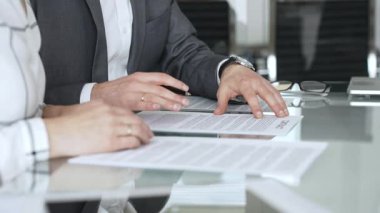 Şirket raporlarını tartışan iş adamlarının elleri, modern ofiste yapılan bir şirket toplantısında finansal tabloları ve verileri analiz ediyor.