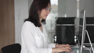 İş kadını verileri yönetir ve çağdaş bir ofiste bilgisayar ekranında finansal grafikleri analiz eder, raporlara ve iş stratejisine odaklanır, üretkenliği ve kurumsal başarıyı temsil eder