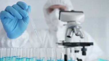 Koruyucu ekipman giyen bilimsel araştırmacıları kapatın, tıbbi araştırma yaparken dikkatlice test tüplerine sıvı pompalayın. Tıp ve bilim konsepti.