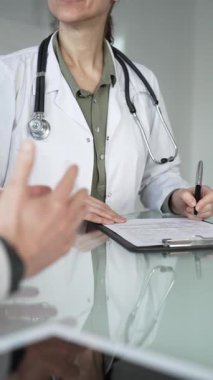 Doktor panoya yazı yazıyor, tıbbi bir randevu sırasında bir hastayla sağlık hakkında konuşuyor, profesyonel bakımı destekliyor. Tıp, sağlık ve bilim konsepti