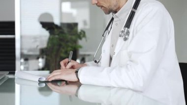 Steteskoplu beyaz önlüklü bir doktor klinikte tıbbi bakım ve profesyonel hizmetler sağlayan bir belge hazırlıyor. Tıp, sağlık ve bilim konsepti