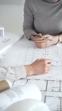 Mimarlar planları ve mimari modelleri inceliyor, profesyonel bir ofis toplantısında tasarım ve şehir planlamasını tartışıyor, gelecekteki inşaat projeleri üzerinde işbirliği yapıyor, kapatıyorlar.