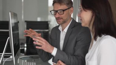 İş arkadaşları bilgisayar, kadın ve erkek birlikte çalışıyor, fikirleri paylaşıyor ve başarılı bir mesleki tartışma ve takım çalışması sırasında gülümsüyor.