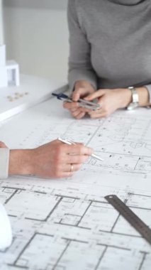 Mimarlar planları ve mimari modelleri inceliyor, profesyonel bir ofis toplantısında tasarım ve şehir planlamasını tartışıyor, gelecekteki inşaat projeleri üzerinde işbirliği yapıyor, kapatıyorlar.