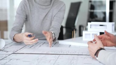 Mimarlar proje planları üzerinde işbirliği yapıyor, mimari tasarımları tartışıyor, inşaat planları geliştiriyor, ofis masasında kavramsal bir model ev yaratıyor, kapatıyorlar.