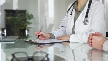 Doktor panoya yazı yazıyor, tıbbi bir randevu sırasında bir hastayla sağlık hakkında konuşuyor, profesyonel bakımı destekliyor. Tıp, sağlık ve bilim konsepti