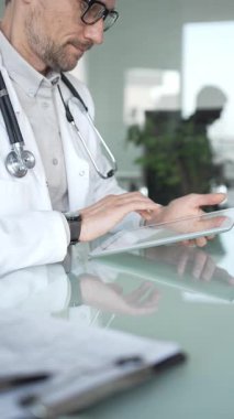 Steteskop takan profesyonel bir doktor, modern bir ofiste sağlık hizmetleri veri yönetimi ve teşhisi için dijital tablet kullanıyor. Tıp, sağlık ve bilim konsepti