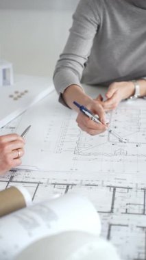 Mimarlar planları ve mimari modelleri inceliyor, profesyonel bir ofis toplantısında tasarım ve şehir planlamasını tartışıyor, gelecekteki inşaat projeleri üzerinde işbirliği yapıyor, kapatıyorlar.