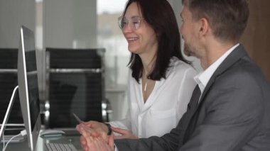 Ofis toplantısında işbirliği yapan iş adamları, bir meslektaşıyla mali raporlar, strateji ve pazar analizi tartışırken masaüstü ekranındaki verilere işaret eden kadın