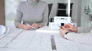 Mimarlar proje inşaatında işbirliği yapıyor, planlar ve mimari modelleri tartışıyor, kentsel planlama ve yeni bir modern konut yapısının iç tasarımı üzerinde yoğunlaşıyor, kapatılıyor