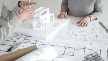 Mimarlar proje planları üzerinde işbirliği yapıyor, mimari tasarımları tartışıyor, inşaat planları geliştiriyor, ofis masasında kavramsal bir model ev yaratıyor, kapatıyorlar.