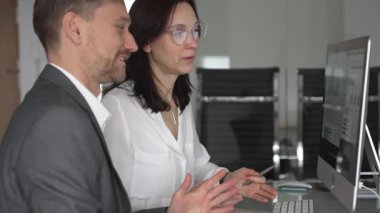 Ofis toplantısında işbirliği yapan iş adamları, bir meslektaşıyla mali raporlar, strateji ve pazar analizi tartışırken masaüstü ekranındaki verilere işaret eden kadın