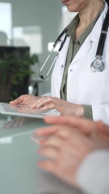 Ofis masasında steteskop kullanan beyaz önlüklü doktor, tele sağlık ve klinik bakım yenilikleri için dijital hasta verilerini inceliyor. İlaç ve sağlık hizmetleri kavramı