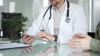 Beyaz önlüklü doktor bir hastayla birlikte tıbbi verileri inceliyor, dijital sağlık hizmetleri ve modern klinik hizmetlerine odaklanıyor. Tıp, sağlık ve bilim konsepti