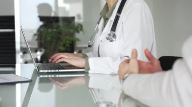 Bir hastane ofisinde dizüstü bilgisayar kullanarak hastalara sağlık sigortasını online danışma sırasında açıklayan bir tıbbi uzman. Tıp, sağlık ve bilim konsepti