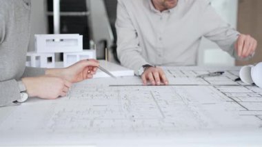 Mimari planlar ve inşaat planları üzerinde işbirliği yapan mimarlar, mühendislik projesinin detaylarını tartışan, bir ofiste tasarım araçları ve dijital tablet kullanan mimarlar