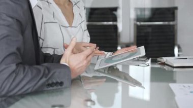 İş arkadaşları, modern bir ofisteki bir tabletin mali tablolarını inceleyerek strateji, veri analizi ve planlama alanlarında işbirliği yapıyorlar. İş adamları konsepti