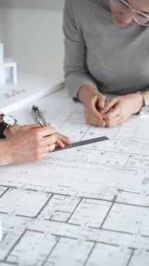 Mimarlar planları ve mimari modelleri inceliyor, profesyonel bir ofis toplantısında tasarım ve şehir planlamasını tartışıyor, gelecekteki inşaat projeleri üzerinde işbirliği yapıyor, kapatıyorlar.