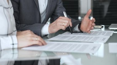 Şirket raporlarını tartışan iş adamlarının elleri, modern ofiste yapılan bir şirket toplantısında finansal tabloları ve verileri analiz ediyor.