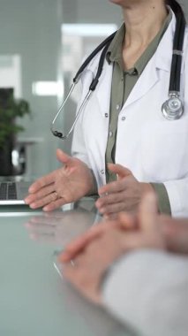 Beyaz önlüklü ve steteskoplu kadın doktor, danışma sırasında dizüstü bilgisayarda daktilo kullanıyor, tıbbi tavsiyeler veriyor ve teknolojiden faydalanıyor. Tıp, sağlık ve bilim konsepti