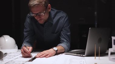 Mimari, profesyonel inşaat planlarını ve mühendislik planlarını geliştiriyor, özenle çiziyor, akşam saatlerinde üretken kalıyor.