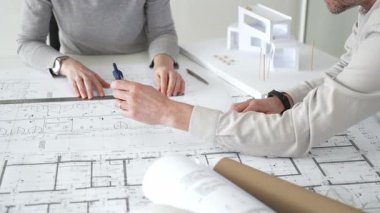 Mimarlar proje planları üzerinde işbirliği yapıyor, mimari tasarımları tartışıyor, inşaat planları geliştiriyor, ofis masasında kavramsal bir model ev yaratıyor, kapatıyorlar.